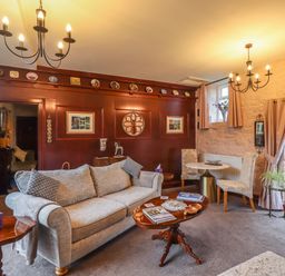 A sitting room with a sofa a coffee table two chairs and decorative plates on a wall at The Barn in Middleton near Ponteland