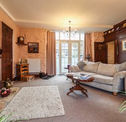 A living room with a sofa coffee table fireplace and large windows at The Barn in Middleton near Ponteland