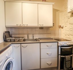 A kitchen with washing machine sink cabinets stove and kettle at The Barn in Middleton near Ponteland