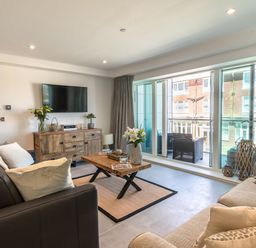 A living room with sofas a wooden coffee table and a TV on a wooden cabinet by sliding glass doors at 31 Cliff Edge in Newquay
