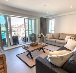 A living room with two sofas a wooden coffee table and sliding glass doors leading to a balcony at 31 Cliff Edge in Newquay