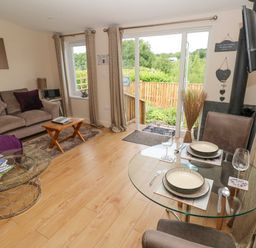 A living room with a sofa coffee tables and a glass dining table near sliding doors at Garden View in Pembroke