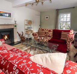 A living room with red patterned sofas a glass coffee table a fireplace and a shelving unit at Kyleatunna Cottage in Ennis County Clare