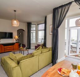 A living room with a green sofa facing a TV mounted on the wall at Apt 3 @ Hunter's Quay in Bridlington