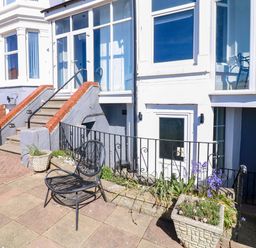 An outdoor area with stairs, a black chair and flower planters at Apt 6 @ Hunter's Quay in Bridlington