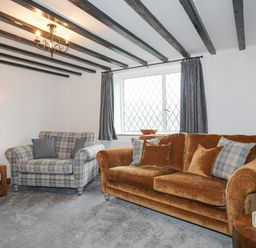 A living room with two sofas a wooden side table and a lamp at 5 The Crescent in Caernarfon
