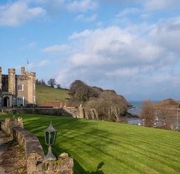 A castle with a lawn and trees at Watermouth Castle, West Tower Apartment in Ilfracombe