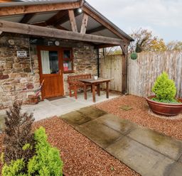 A stone cottage entrance with wooden door bench and table a stone pathway and potted plants at Barn 3 Cwm-twrch Isaf near Ystradgynlais