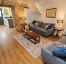 A sitting room with two gray sofas a wooden coffee table and stone walls at The Old Post Office in Praze-An-Beeble