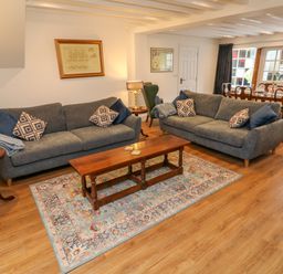 A living room with two gray sofas a wooden coffee table and a dining table in the background at The Old Post Office in Praze-An-Beeble