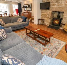 A living room with blue sofas a wooden coffee table a fireplace and wooden furniture at The Old Post Office in Praze-An-Beeble