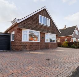 A brick house with a paved driveway and a garage at Meadowfields in Whitby