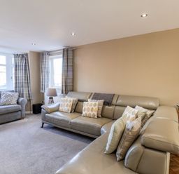 A living room with two sofas pillows a floor lamp curtains and a painting on the wall at Meadowfields in Whitby