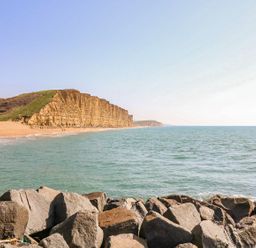 A rocky shoreline with cliffs and a sandy beach by the sea at Alices Cottage in Burton Bradstock