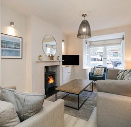 A living room with sofas a coffee table a fireplace and a window at Forty Five in Keswick