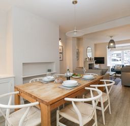 A dining area with a wooden table set for four and a living room with sofas and a TV at Forty Five in Keswick