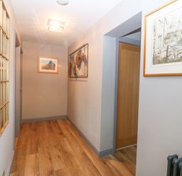 A hallway with wooden flooring paintings on the walls and a mirror at Tyn Rallt Ice Cream Farm Malltraeth near Newborough