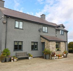 A house with a bench and planters at Tyn Rallt in Newborough