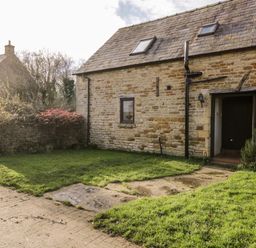 A stone cottage with a tiled roof and grassy yard at Well Cottage in Moreton-In-Marsh