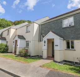 A row of attached residential houses with small front lawns and paved walkways at Manuka in Falmouth