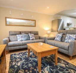 A living room with two grey sofas a wooden coffee table and a patterned rug at Manuka in Falmouth