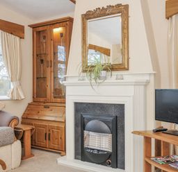 A living room with a fireplace and sofa at Little Malory in St Giles-On-The-Heath