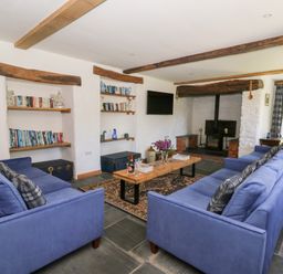 A living room with blue sofas wooden coffee table bookshelves and a fireplace at Glanduad Fawr in Newport Pembrokeshire