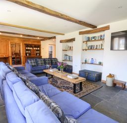 A living room with blue sofas a wooden coffee table and shelves with books at Glanduad Fawr in Newport Pembrokeshire