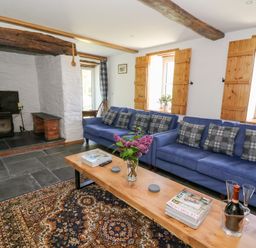 A living room with two blue sofas and a wooden coffee table near a fireplace at Glanduad Fawr in Newport Pembrokeshire