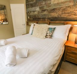 A bedroom with a bed with white linens and rolled towels on the bed at Lakeside 12 in Carnforth