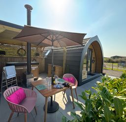 An outdoor seating area with a table umbrella chairs and a wooden cabin at Yes Deer in Ashbourne