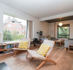 A living room with two wooden lounge chairs with yellow cushions and a window bench with books at Mundays Orford