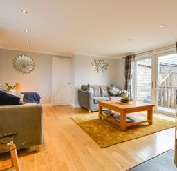 A living room with two sofas a wooden coffee table a yellow rug and glass doors at Lilys Pad in Okehampton