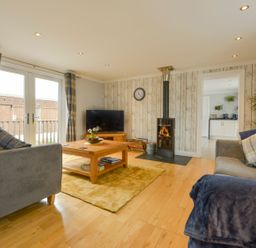 A living room with two sofas a wooden coffee table a television and a wood stove at Lilys Pad in Okehampton