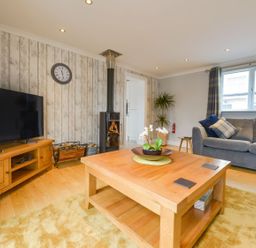 A living room with a wooden coffee table and a gray sofa near a window at Lilys Pad in Okehampton