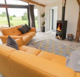 A living room with orange sofas a fireplace and large windows showing a garden at Windy Willows in Okehampton