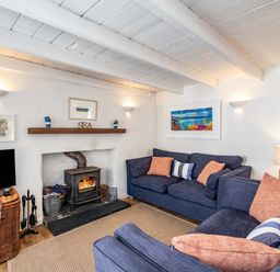 A living room with blue sofas and a wood burning stove at Sea Horses in Port Isaac