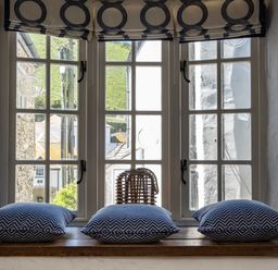 A window with three blue patterned cushions on the wooden sill and a wicker lantern in the middle at Sea Horses Port Isaac