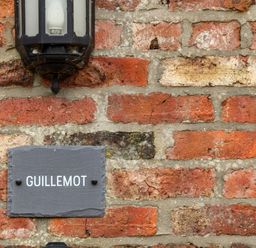 A brick wall with a black lantern and a slate sign with the word Guillemot