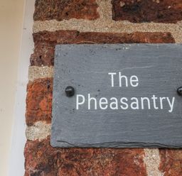 A sign displaying the name 'The Pheasantry' on a brick wall at The Pheasantry in Flamborough