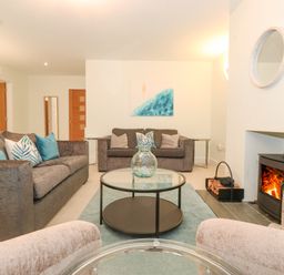 A living room with sofas a glass coffee table a fireplace and wooden doors at Tandarra in Keswick