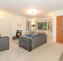A living room with sofas a wood burning stove and a wooden door at Tandarra in Keswick