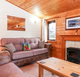 A sitting room with sofas a wooden coffee table a fireplace and a window at Latrigg Lodge Number 9 Burnside Park near Keswick