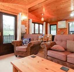 A living room with wooden walls and ceiling with sofas and a dining area at Latrigg Lodge Number 9 Burnside Park near Keswick