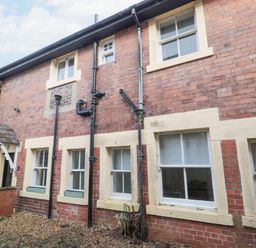 The exterior of a brick building with multiple windows and black drainpipes at Courtyard Cottage in Alnwick