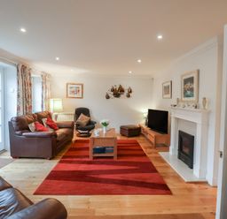 A living room with a sofa, table, and television at 9 Church Farm Rise, Aldeburgh