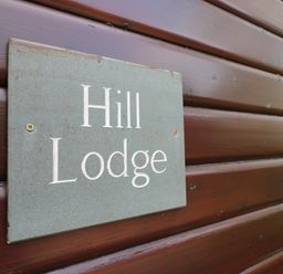 A sign reading Hill Lodge mounted on a wooden exterior wall at Hill Lodge Applethwaite 2 Limefitt Park near Windermere