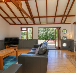A living room with a black leather sofa a wooden coffee table and a television at Bay Tree Lodge 35 Watermouth near Berrynarbor