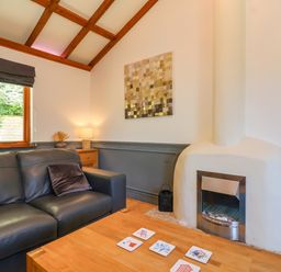 A living room with a black leather sofa a wooden coffee table and a white fireplace at Bay Tree Lodge 35 Watermouth near Berrynarbor