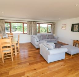 A living room with sofas a dining table and chairs and a television on the wall at Little Owl Barn in Upton Snodsbury